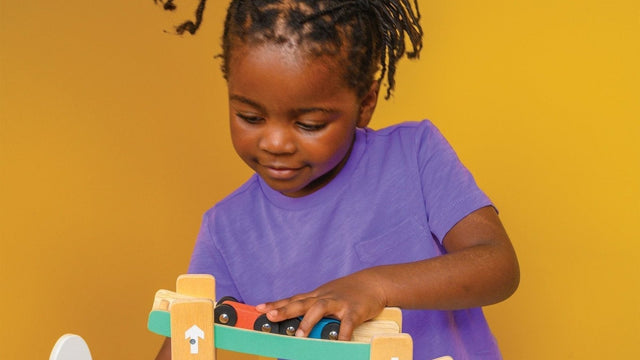 Toddler racing wooden toy cars down a Mentari ramp racer, one of the best toy cars for toddlers