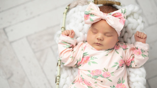Newborn asleep in a soft floral gown and bow — best baby clothing brands 2026 guide from EasyTot