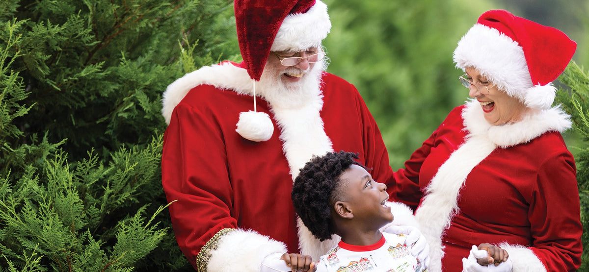 Child laughing with Santa and Mrs. Claus in Christmas pajamas