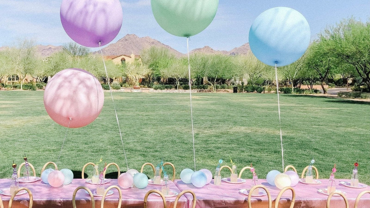 Outdoor baby shower table set on a lawn with oversized pastel balloons and mountain views