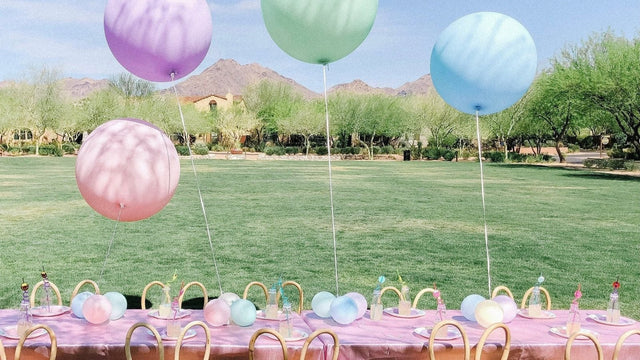 Outdoor baby shower table set on a lawn with oversized pastel balloons and mountain views