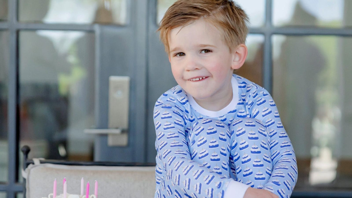 Young boy in soft blue pajamas by a bright window