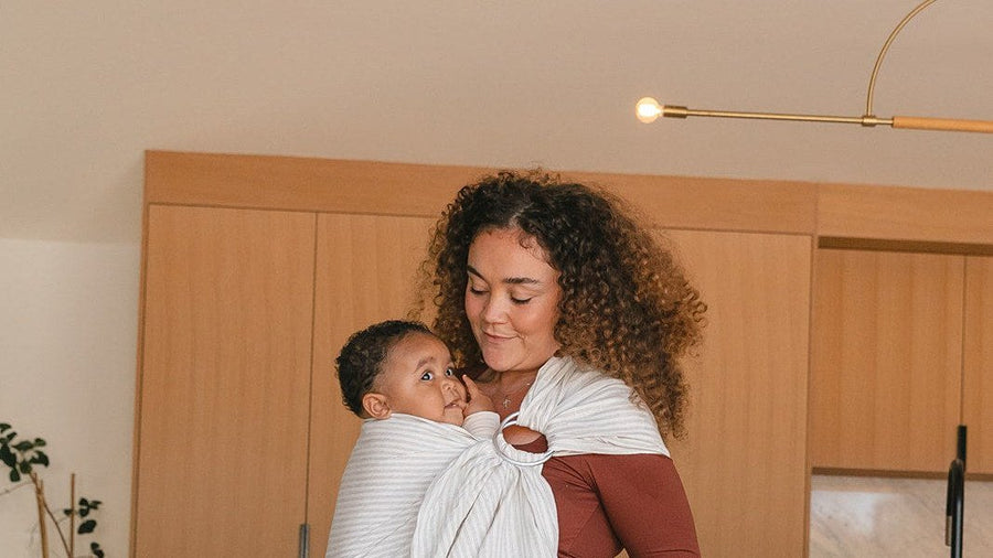 Mother carrying her baby in a ring sling hip carrier