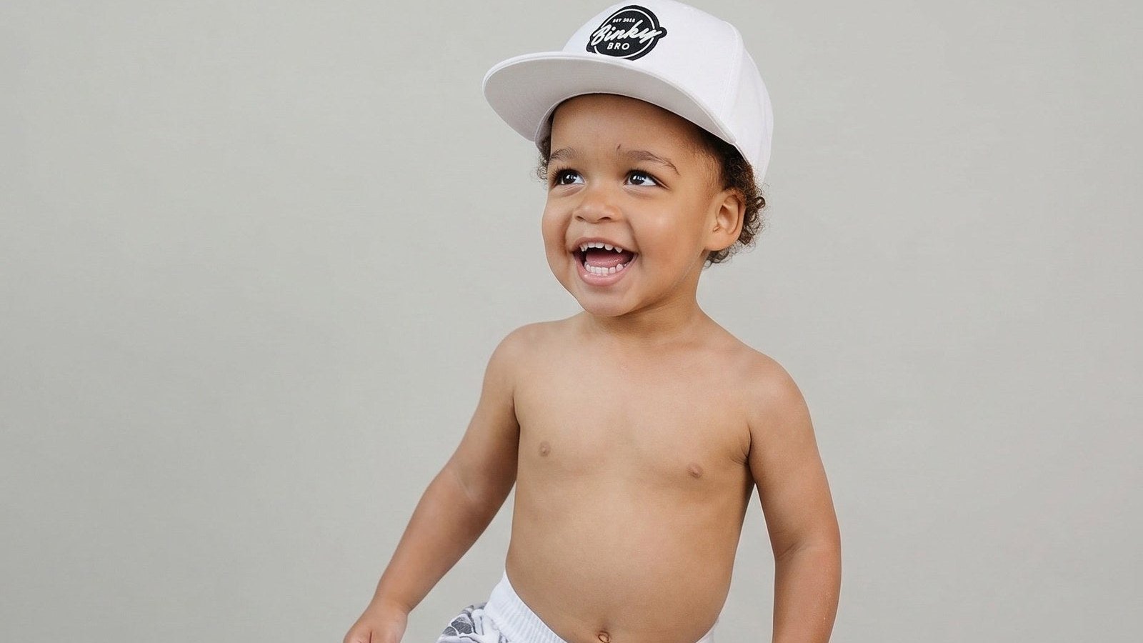 Happy toddler in a sun hat dressed for the pool