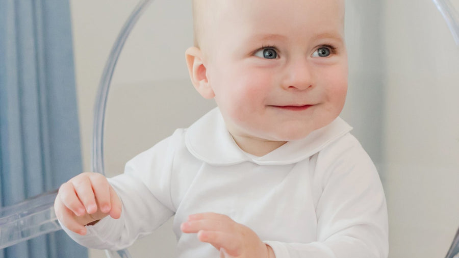 Baby sitting up in a white newborn onesie