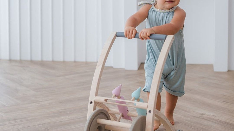 Baby learning to walk with a wooden push walker