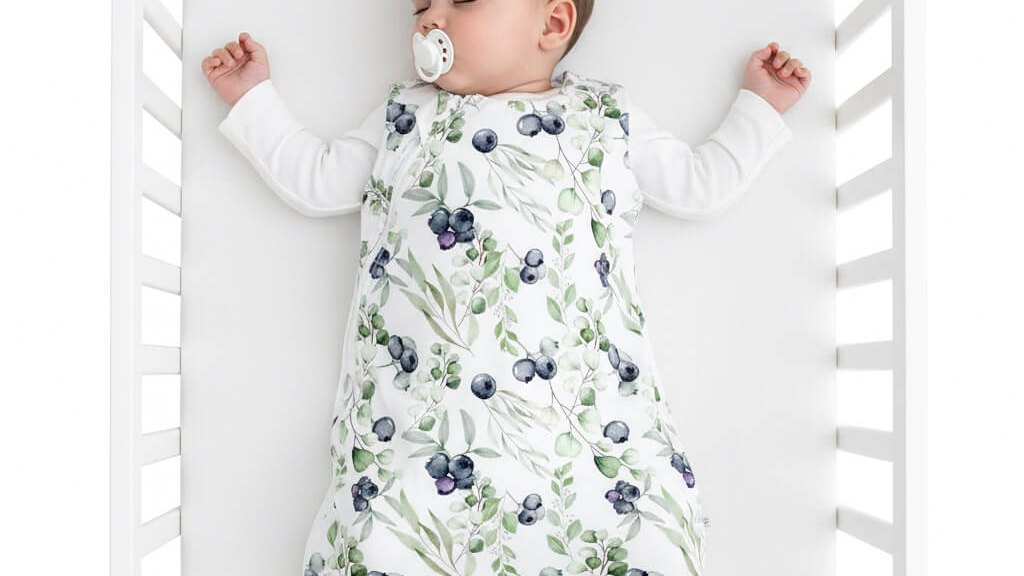 Baby wearing a sleep sack in a crib