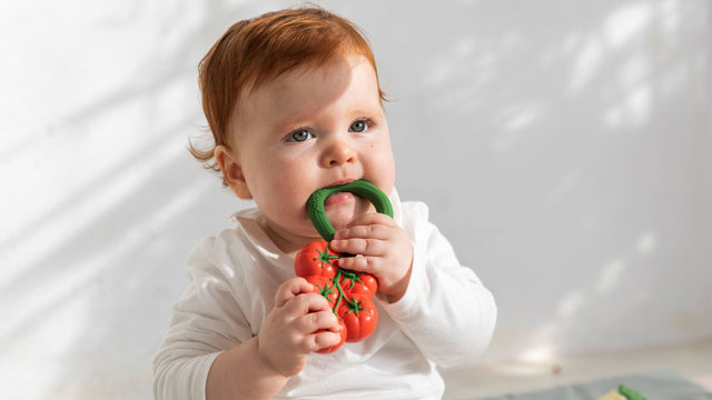 Baby chewing on an Oli & Carol tomato teething rattle