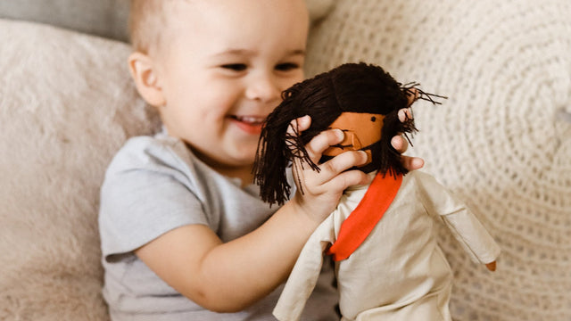Toddler smiling and hugging a Jesus rag doll - Catholic toys and gifts for kids