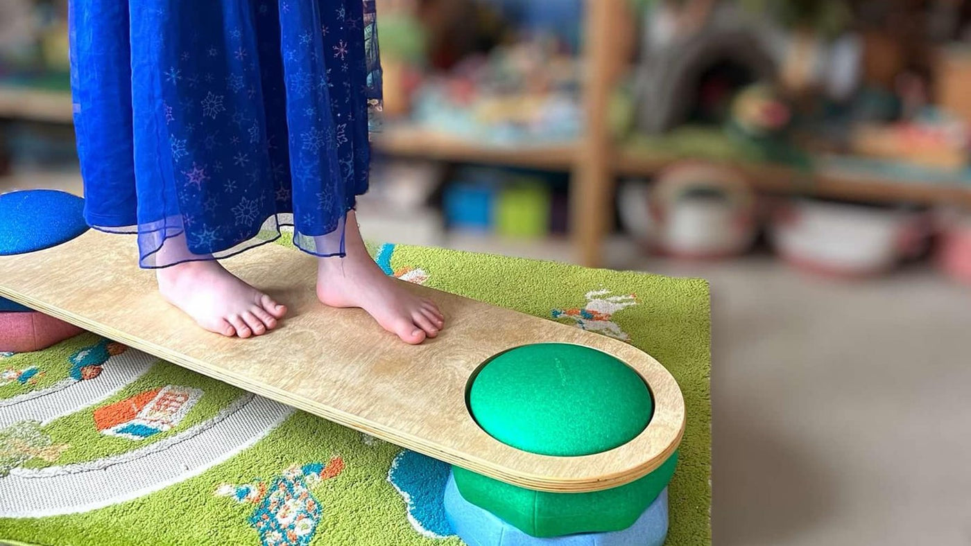 Child balancing on a Green Elephant connector board bridged across stepping stones in a playroom