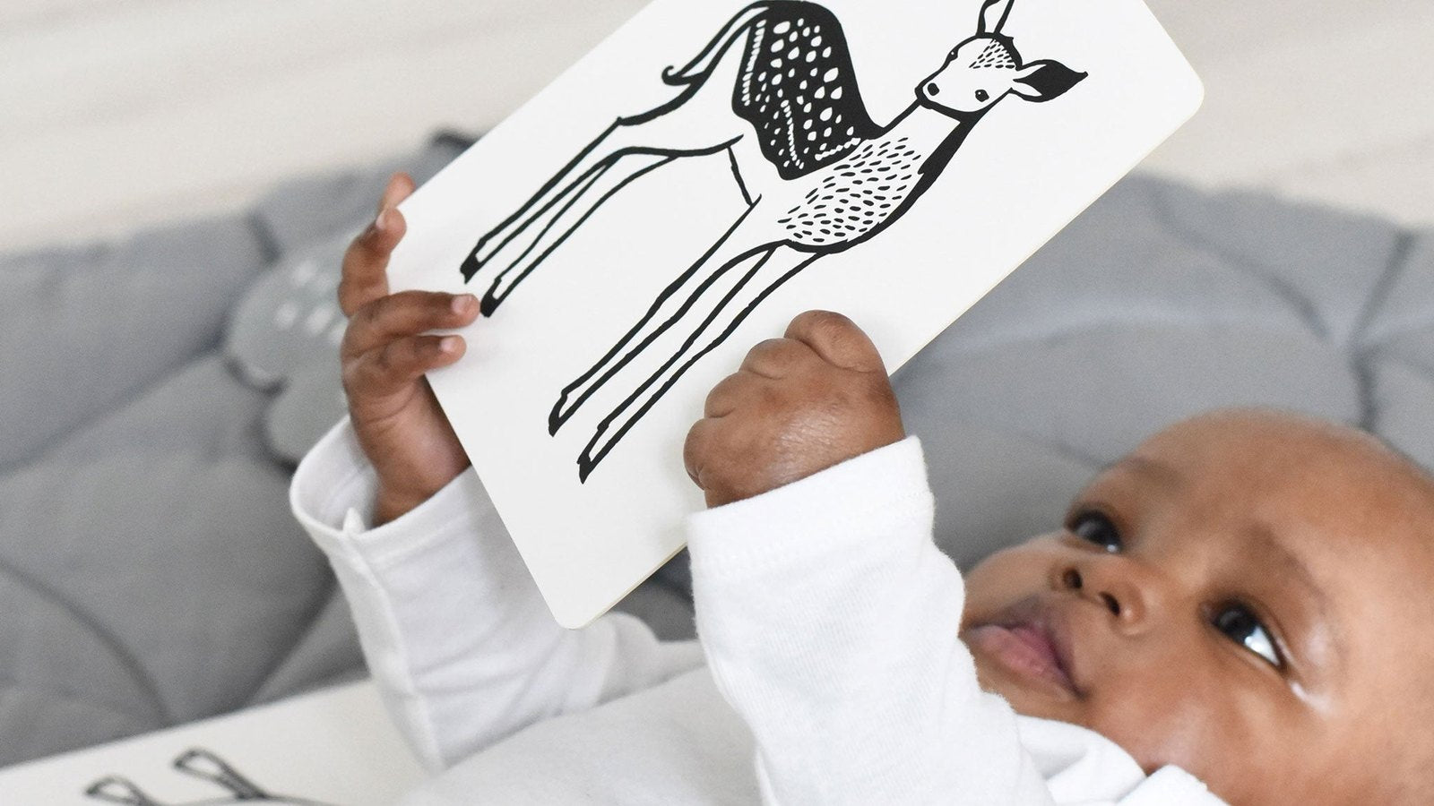 Newborn holding a black and white high contrast art card during floor time