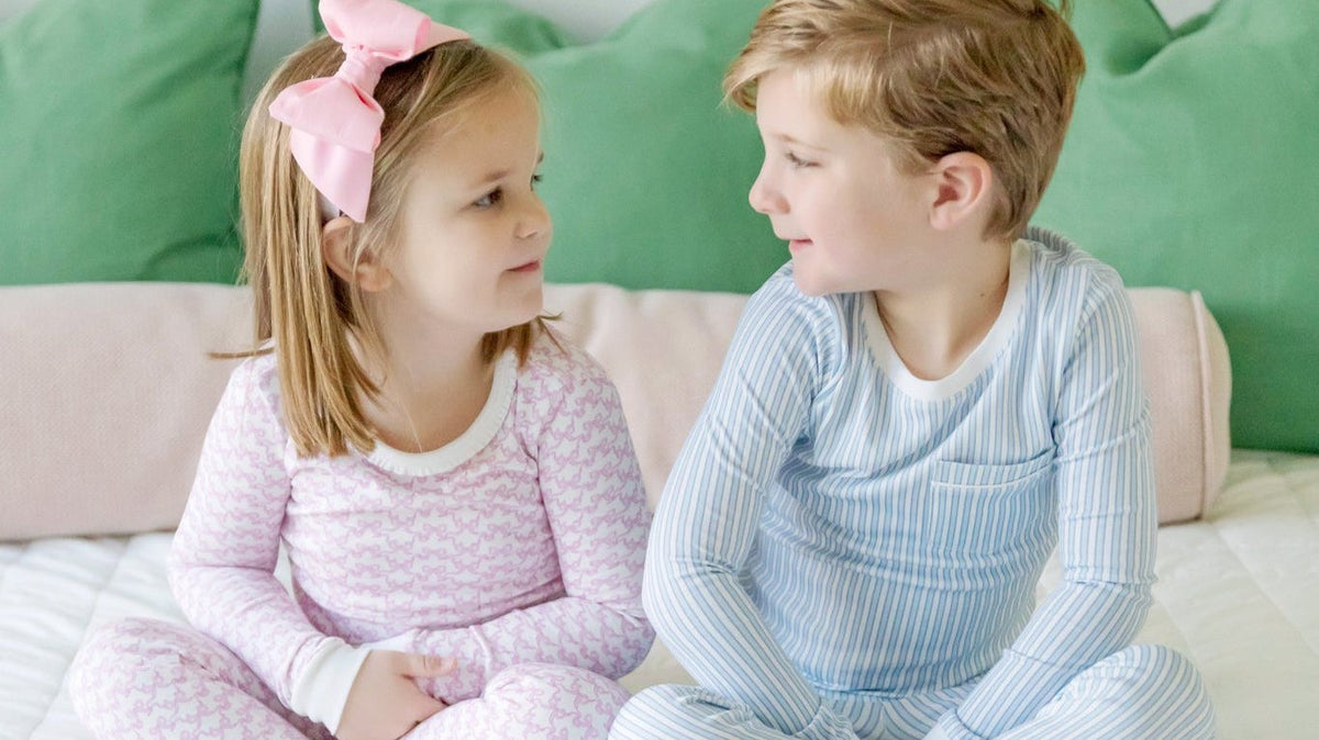 Two kids in Lila + Hayes pima cotton pajamas sitting together on a bed