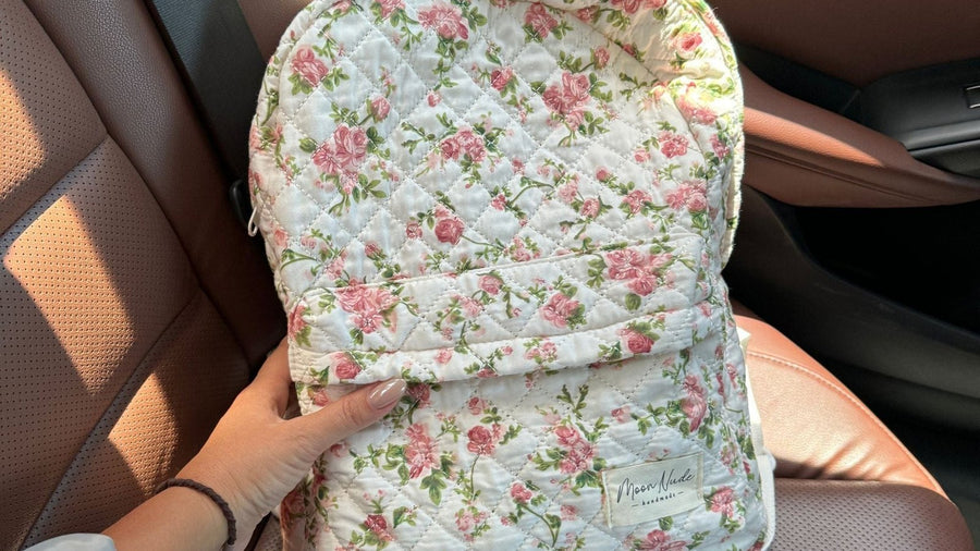 Moon Nude quilted floral backpack held on a car seat in warm light