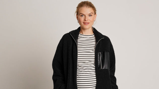 Expectant mother in a striped maternity top and open black jacket