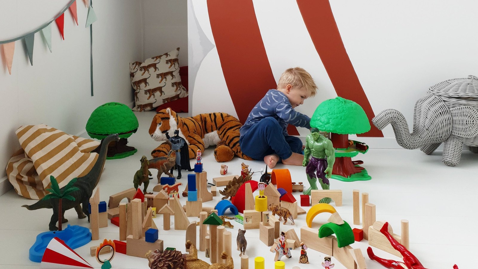 Toddler playing with blocks and toys spread across a playroom floor - the daily toy explosion good toy storage and playroom organization tames