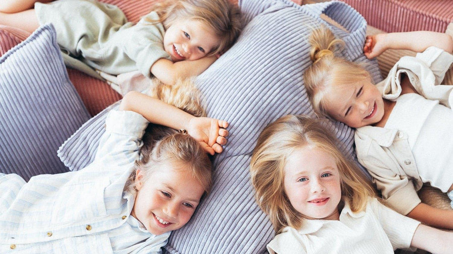 Four happy kids piled on Wigiwama corduroy beanbags and play couch cushions