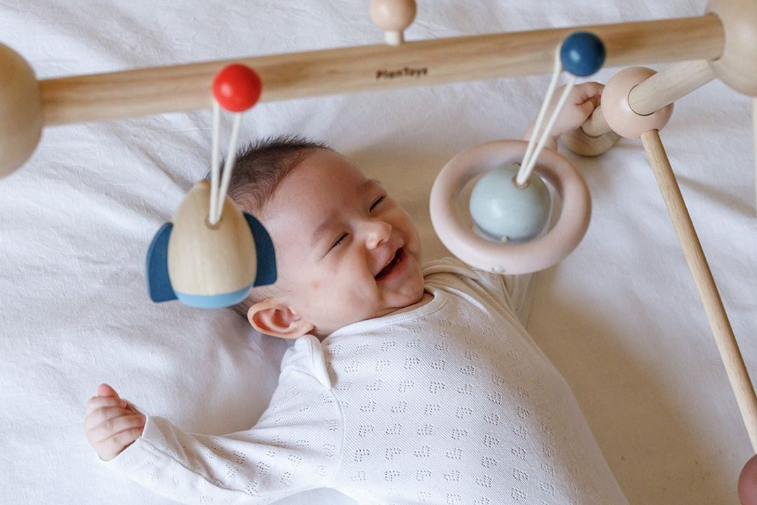Baby playing under an activity gym