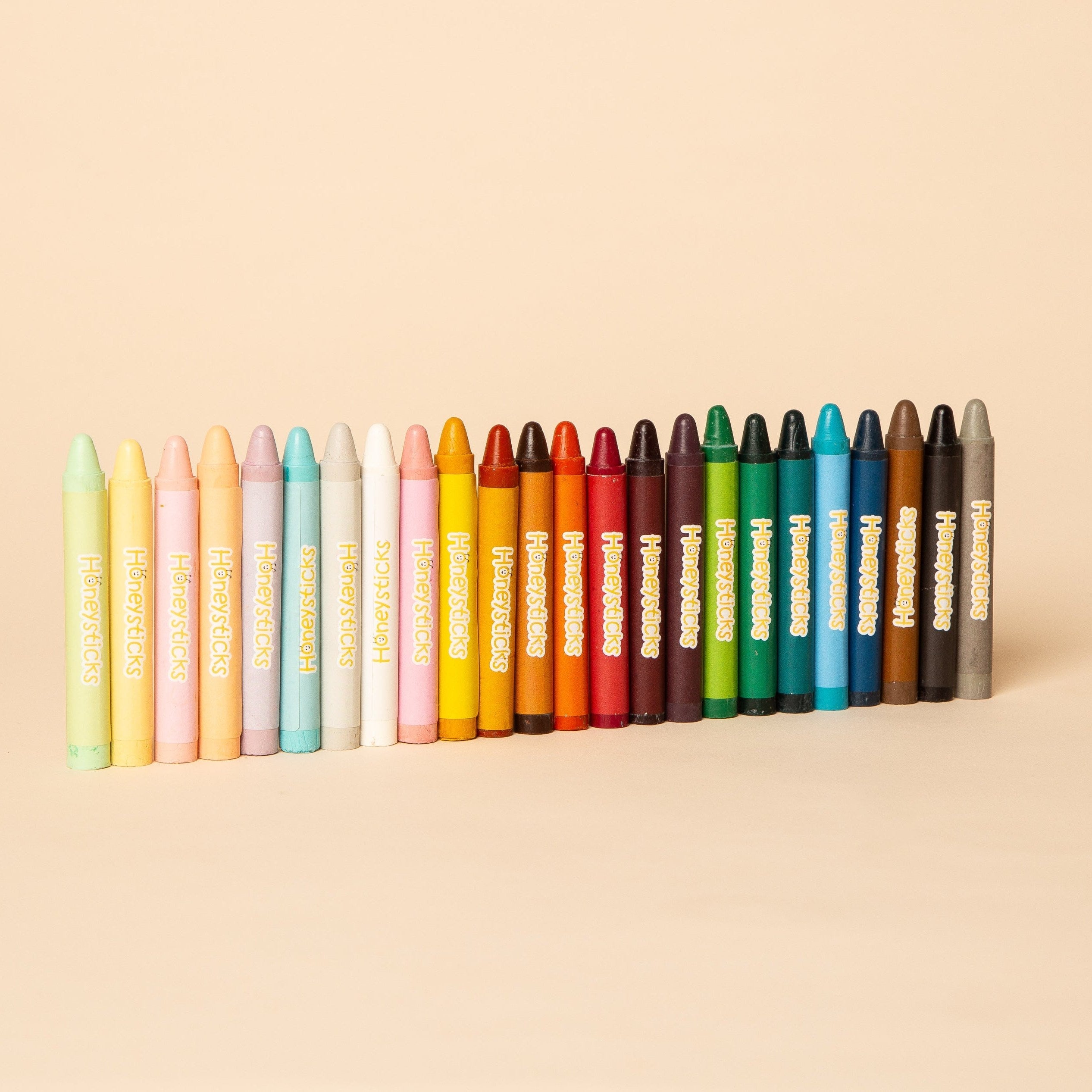 Colorful beeswax crayons lined up on a warm cream background